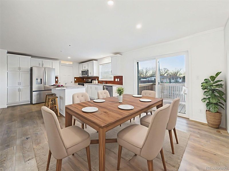 Dining Room Virtually This bright, open-concept kitchen and dining space features crisp white cabinetry, stainless steel appliances, and a center island with bar seating. A sliding glass door leads directly to the back deck, perfect for indoor-outdoor dining.