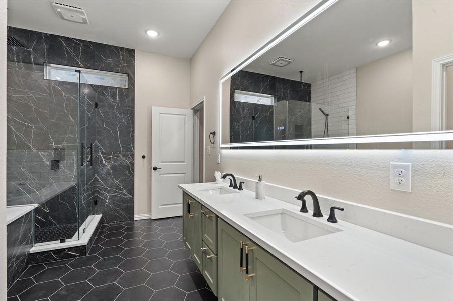 Full bath featuring double vanity, a marble finish shower, dark tile patterned flooring, and recessed lighting Full bath featuring double vanity, a marble finish shower, dark tile patterned flooring, and recessed lighting