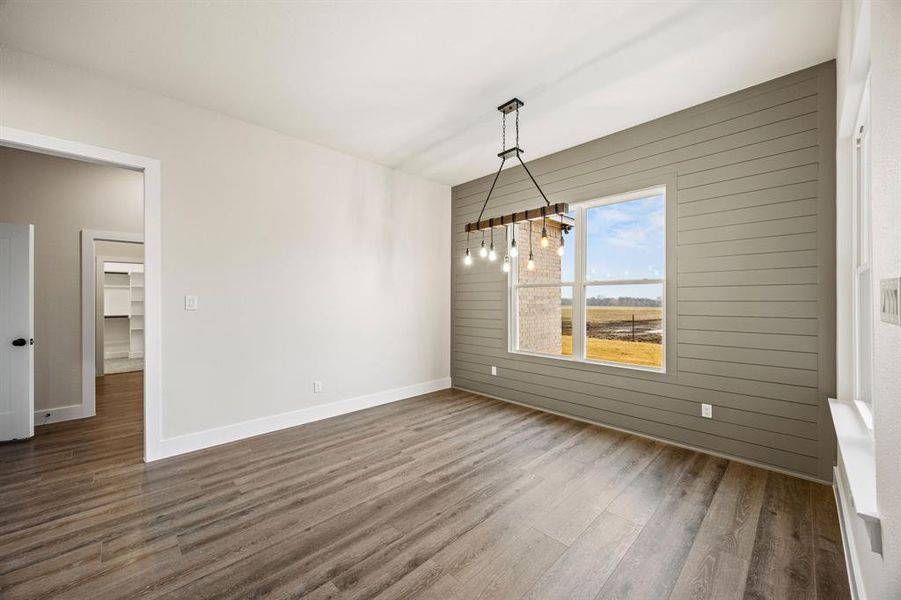 Unfurnished dining area featuring wood walls and wood finished floors Unfurnished dining area featuring wood walls and wood finished floors