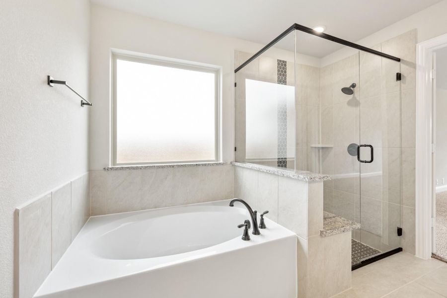 Master bathroom with soaking tub, glass-enclosed walk-in shower, and tile surround in neutral tones Master bathroom with soaking tub, glass-enclosed walk-in shower, and tile surround in neutral tones