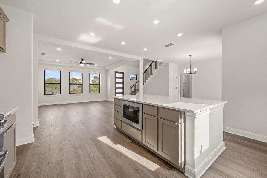 Spacious kitchen featuring built in microwave drawer, large center island, abundant storage, breakfast bar, eat-in kitchen dining area, modern style range hood, stainless appliances, and pantry