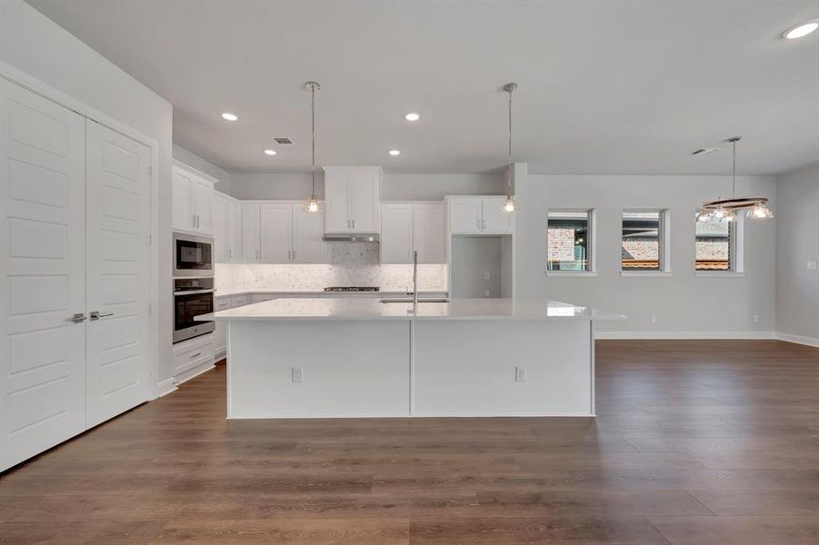 Kitchen featuring white cabinetry, a kitchen island with sink, dark wood-type flooring, and stainless steel appliances