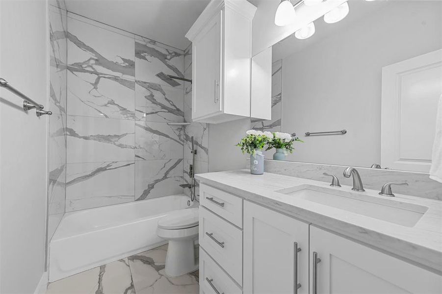 Full bathroom with vanity, tiled shower / bath combo, and toilet