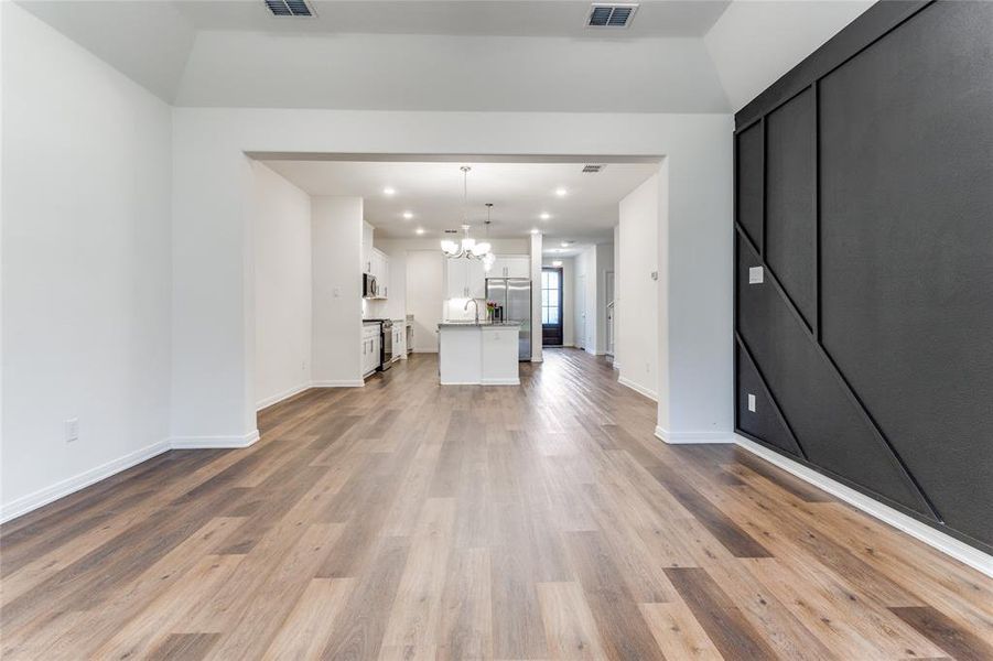 Unfurnished living room featuring a notable chandelier, light wood-type flooring, and sink