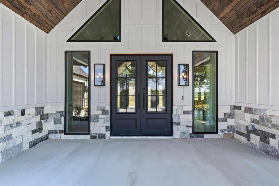 View of exterior entry with board and batten siding, a patio, and stone siding View of exterior entry with board and batten siding, a patio, and stone siding