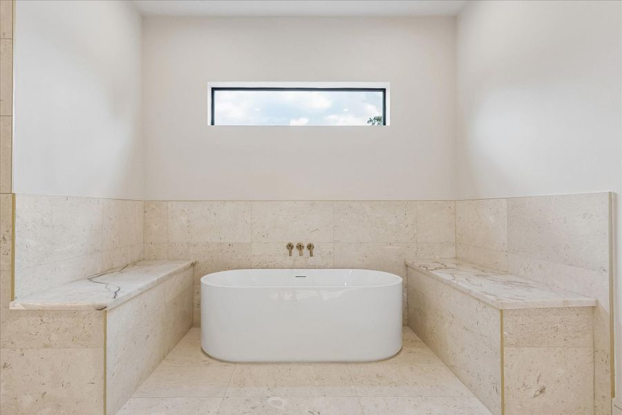 Unwind in a freestanding soaking tub framed by natural stone surrounds, creating a true spa inspired retreat. Elevated finishes, warm brass fixtures, and abundant natural light bring a sense of calm to the primary bath.