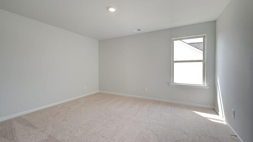 Carpeted secondary bedroom with neutral walls and natural light in the Clarity at Brighton in Locust Grove, GA.