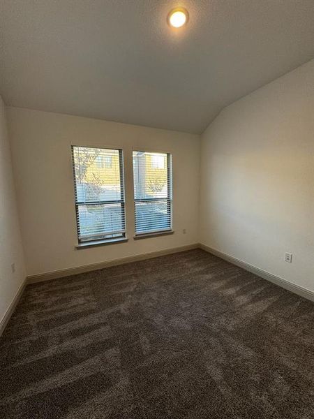 Carpeted empty room with vaulted ceiling