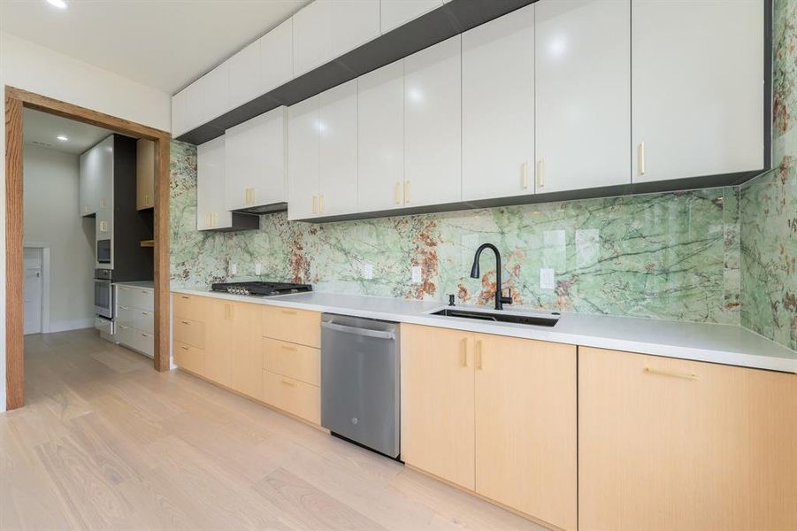 Kitchen with modern cabinets, light wood finished floors, stainless steel appliances, light brown cabinetry, and recessed lighting
