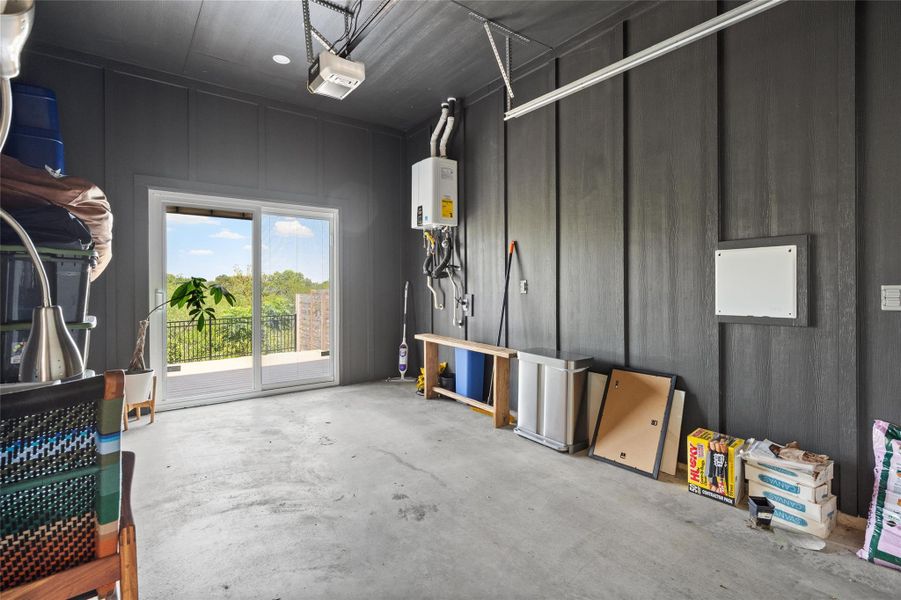 A spacious garage with a sleek gray interior and direct access to an outdoor patio with verdant views. A spacious garage with a sleek gray interior and direct access to an outdoor patio with verdant views.