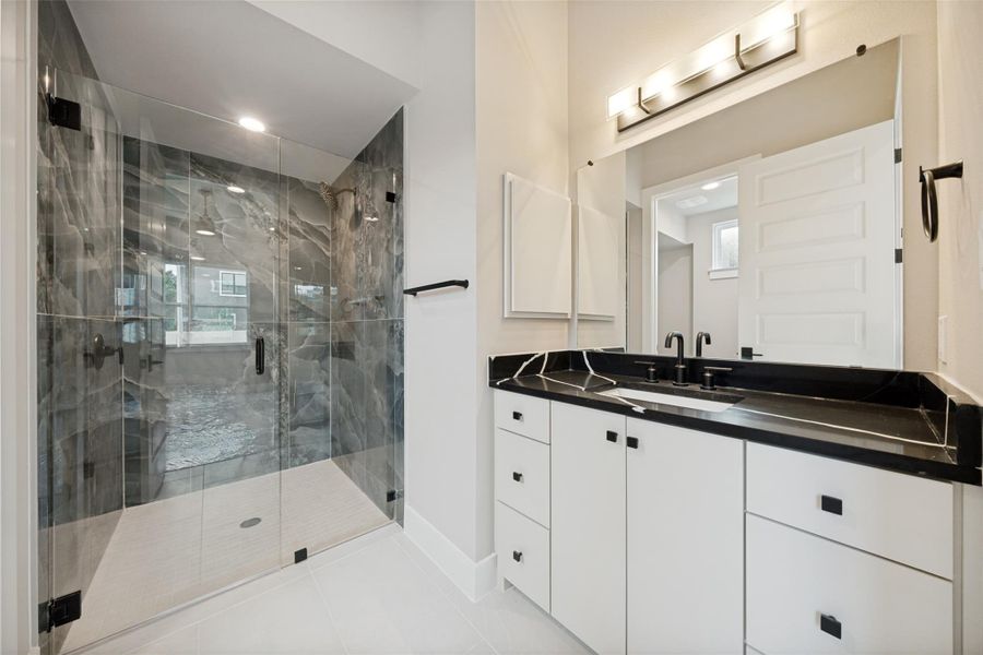 A refined attached bathroom on secondary primary featuring a contemporary vanity with a sleek countertop and a spacious walk-in shower. A refined attached bathroom on secondary primary featuring a contemporary vanity with a sleek countertop and a spacious walk-in shower.