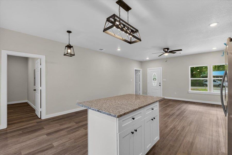Stone-topped counters and wood-look flooring anchors this open central layout. Stone-topped counters and wood-look flooring anchors this open central layout.