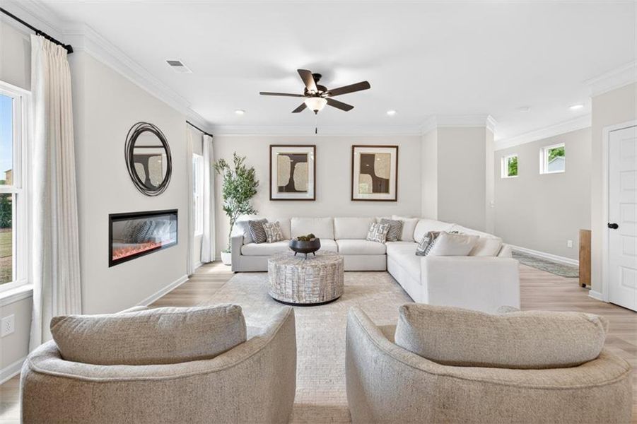 Spacious living area featuring light wood-finish flooring and crown molding
