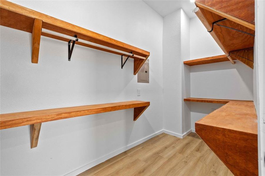 Spacious closet with light wood-type flooring and electric panel