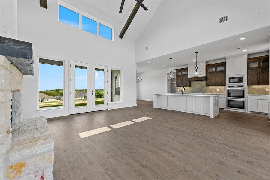 Unfurnished living room featuring french doors, a fireplace, dark hardwood / wood-style flooring, high vaulted ceiling, and sink