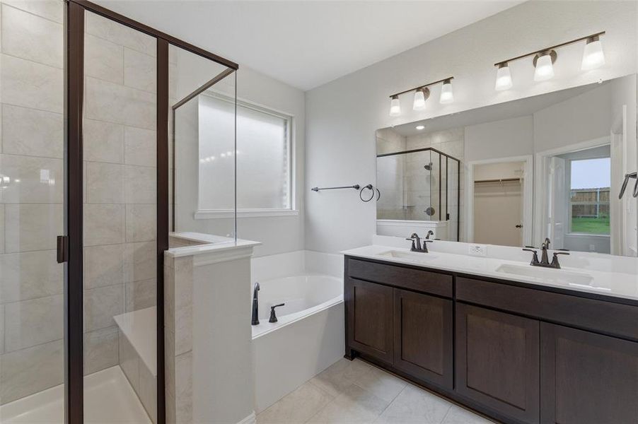 Bathroom featuring a dual-sink vanity with dark wood cabinetry, white countertops, and matte black fixtures