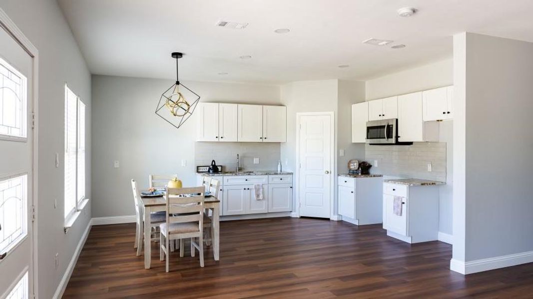 Kitchen featuring light stone counters, backsplash, decorative light fixtures, dark hardwood / wood-style flooring, and white cabinets Kitchen featuring light stone counters, backsplash, decorative light fixtures, dark hardwood / wood-style flooring, and white cabinets