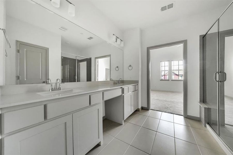 Full bath featuring a stall shower, double vanity, light tile patterned flooring, and light colored carpet Full bath featuring a stall shower, double vanity, light tile patterned flooring, and light colored carpet