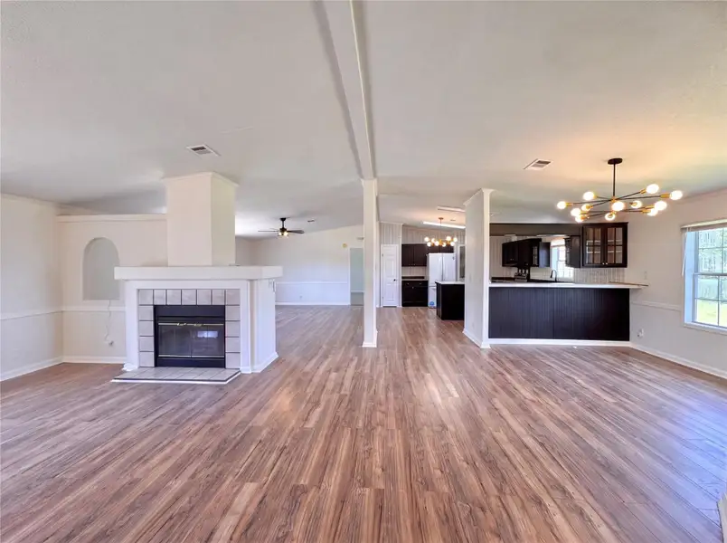 An open floorplan centers on a tiled fireplace with rich wood-look flooring throughout.