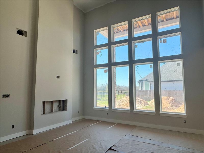 Wall of windows in spacious family room - water view with modern electric fireplace
