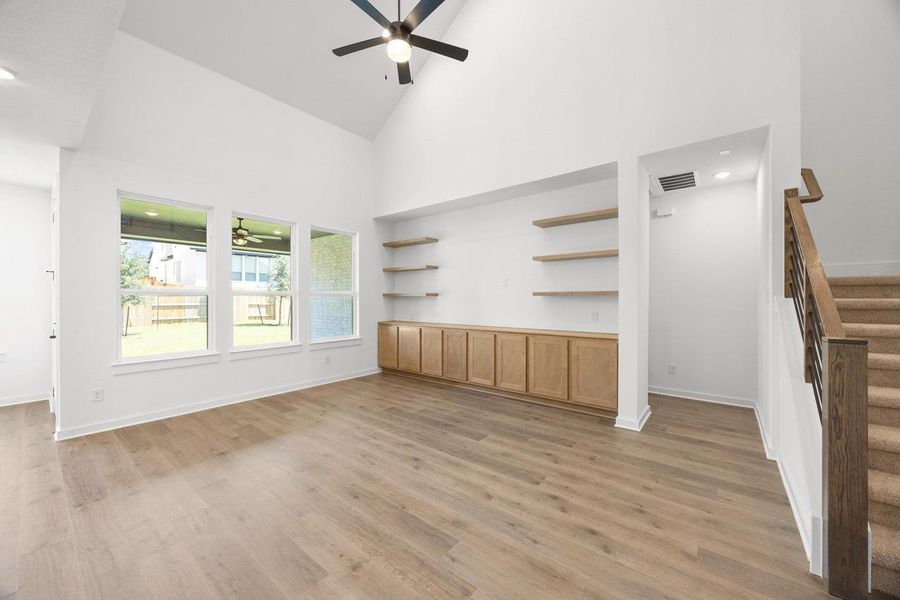 Unfurnished living room featuring high vaulted ceiling, stairs, ceiling fan, and light wood-style flooring Unfurnished living room featuring high vaulted ceiling, stairs, ceiling fan, and light wood-style flooring