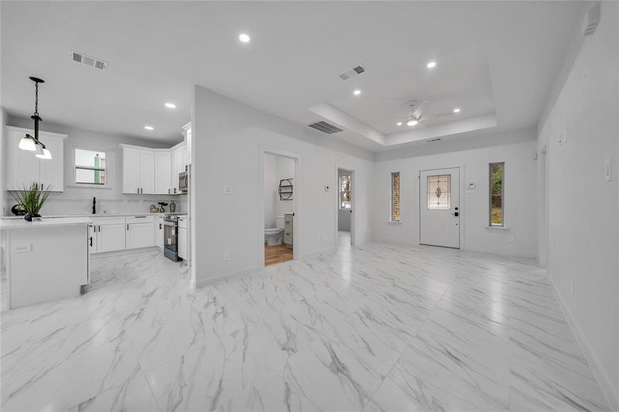 Unfurnished living room featuring ceiling fan and a tray ceiling