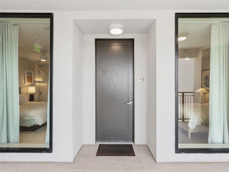 Entryway featuring a dark paneled door, a flush-mount overhead light fixture, and light-colored tile flooring Entryway featuring a dark paneled door, a flush-mount overhead light fixture, and light-colored tile flooring