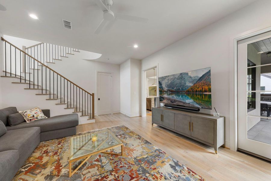 Light-filled living area with wood flooring, direct patio access through glass doors, & convenient access to a full bathroom—ideal for guests or seamless indoor-outdoor living.