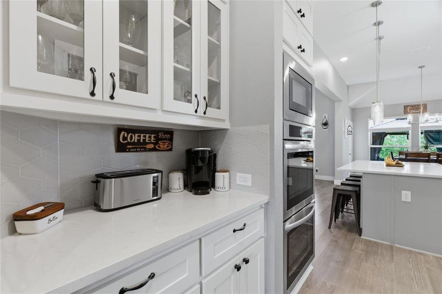 Modern kitchen featuring white shaker cabinetry with dark hardware, a white countertop, and a light gray geometric tile backsplash