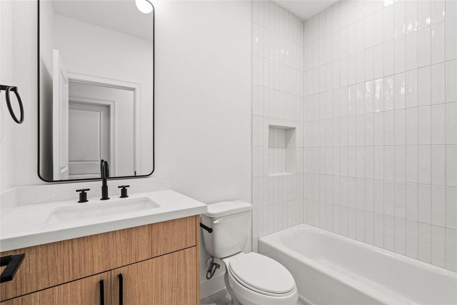 Modern secondary bathroom with sleek vanity, black fixtures, and tiled tub/shower combo.