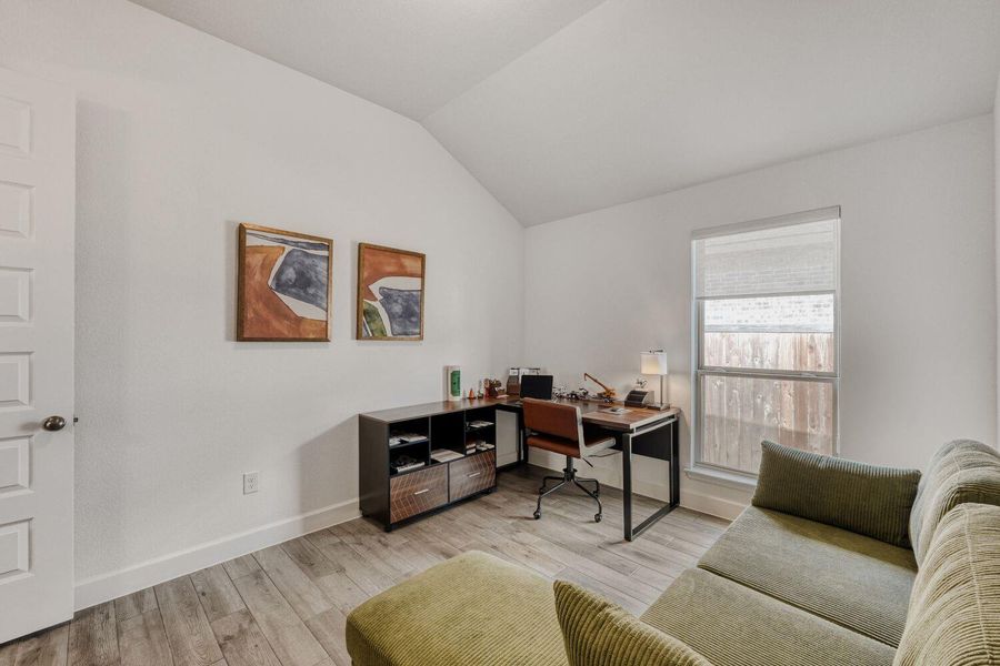 Home office with light wood-style floors and lofted ceiling