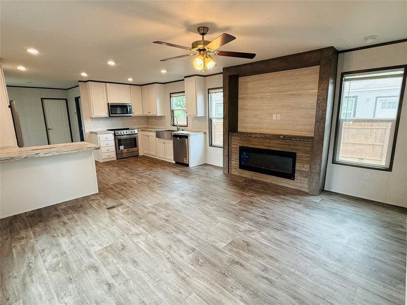 Kitchen featuring stainless steel appliances, a large fireplace, light countertops, a sink, and white cabinetry