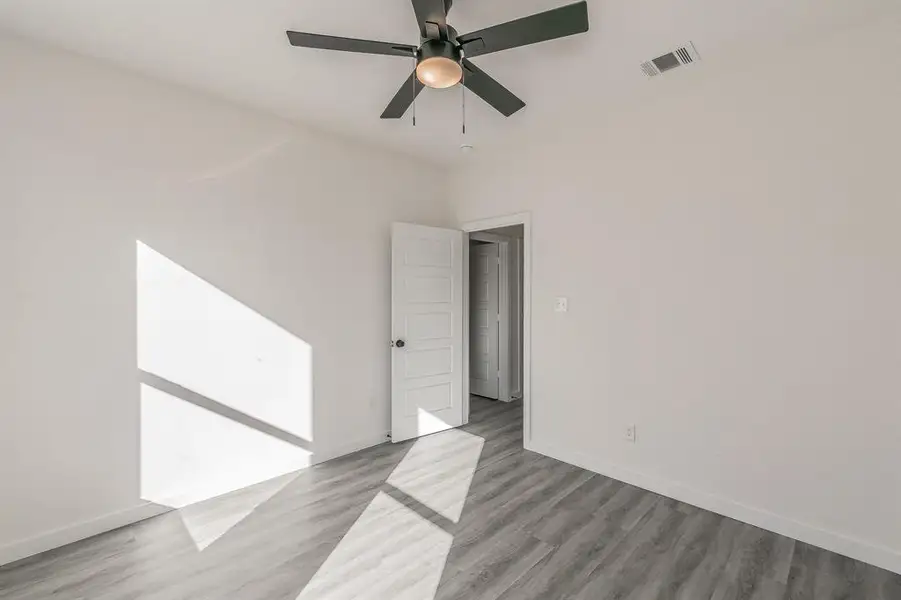 Spare room with a ceiling fan, baseboards, visible vents, and wood finished floors