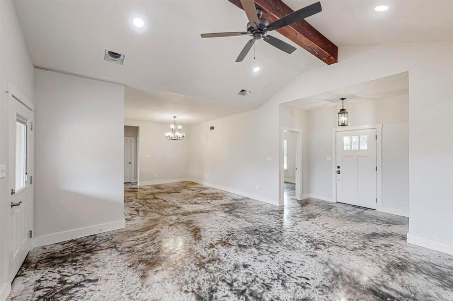 Entryway with ceiling fan with notable chandelier, vaulted ceiling with beams, and a healthy amount of sunlight