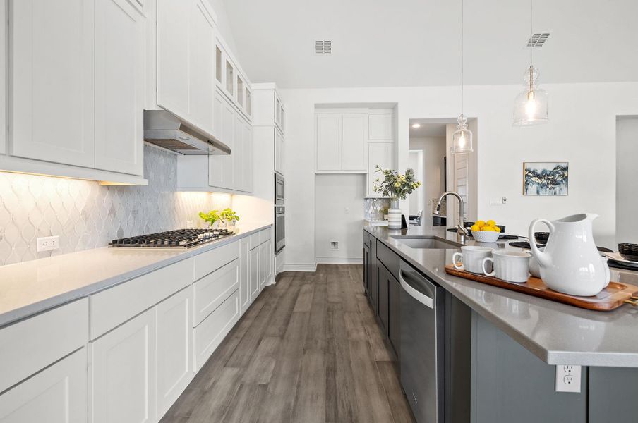 Kitchen with dark wood finished floors, white cabinets, appliances with stainless steel finishes, glass insert cabinets, and hanging light fixtures