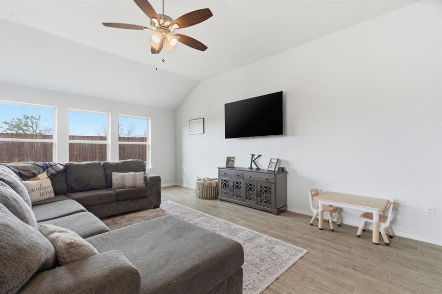 Living area featuring wood finished floors, vaulted ceiling, and ceiling fan