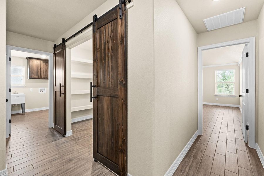 Hall featuring healthy amount of natural light, wood like tiled floors, and a barn door Hall featuring healthy amount of natural light, wood like tiled floors, and a barn door