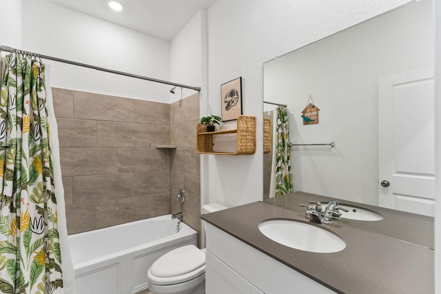 A sleek vanity with a wide mirror complements the clean-lined tub and tiled shower surround in this bright bathroom.
