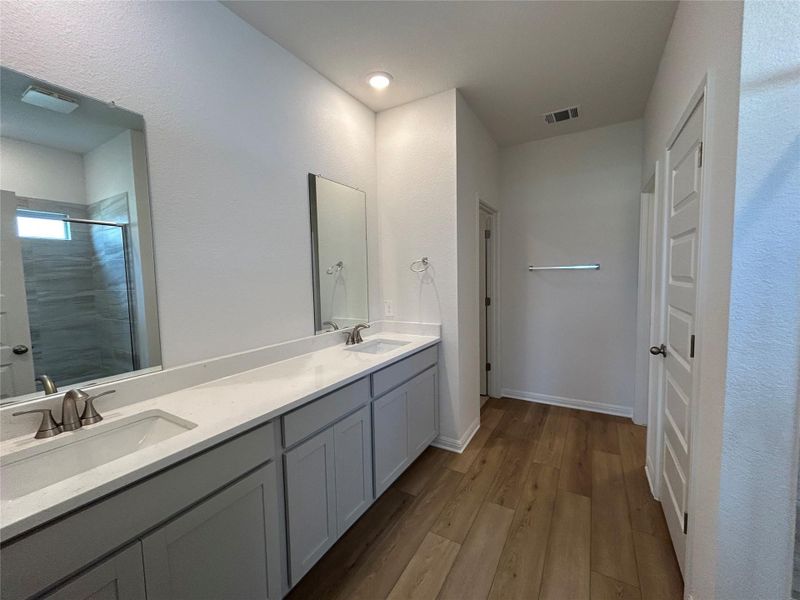 Full bathroom featuring a shower stall, dark wood-style flooring, double vanity, and a textured wall Full bathroom featuring a shower stall, dark wood-style flooring, double vanity, and a textured wall