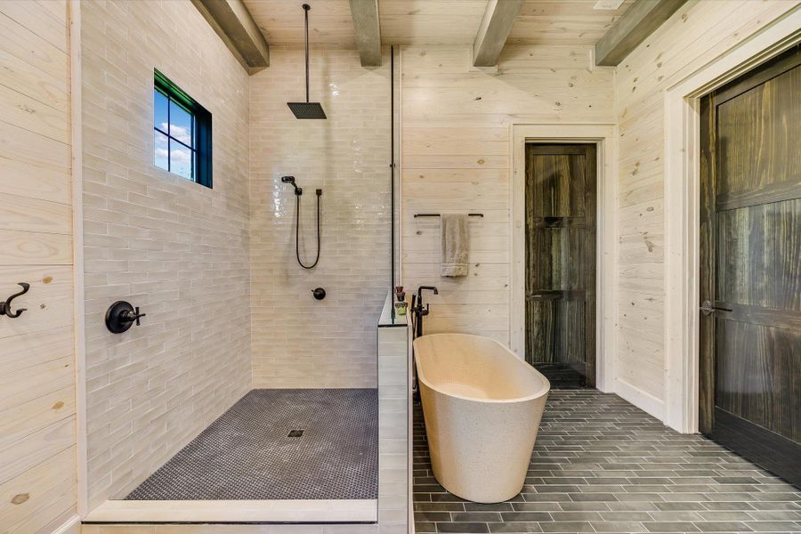 Bathroom with a freestanding bath, wood walls, a walk in shower, and beamed ceiling