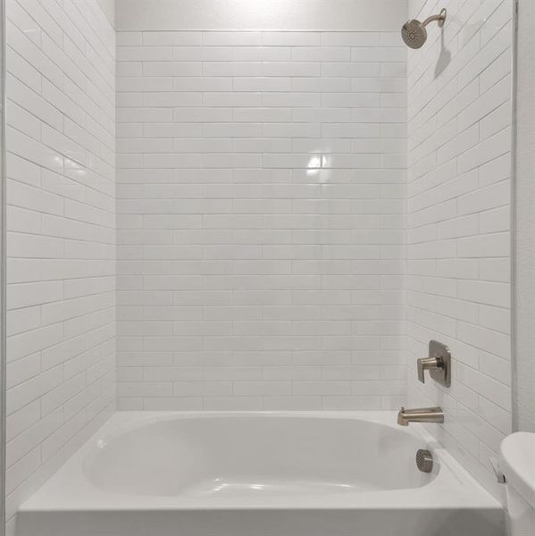 Bathroom with tiled shower / bath and toilet