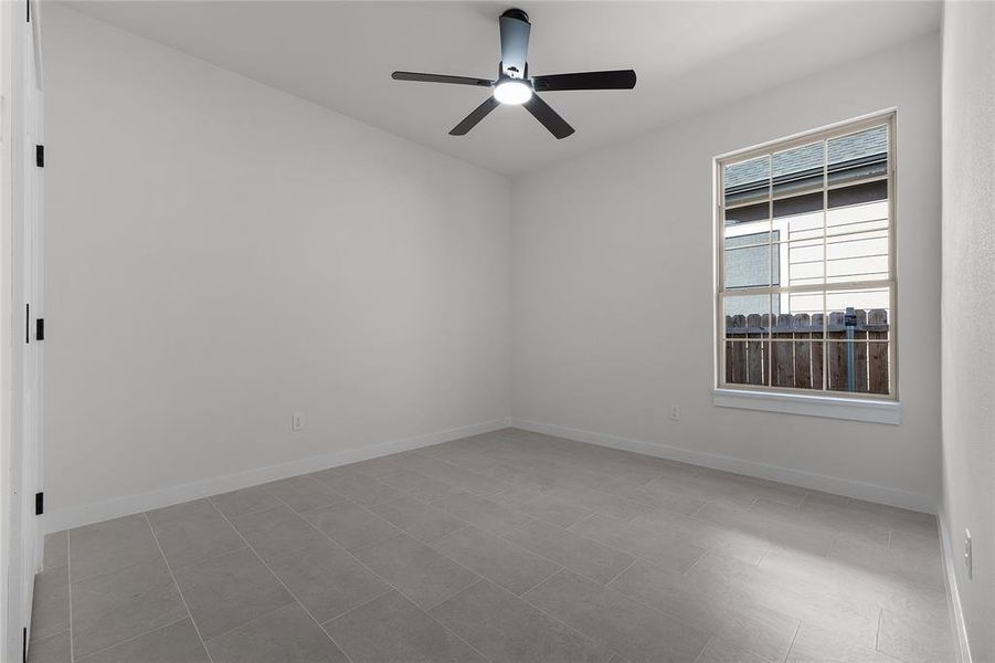 Tiled spare room featuring ceiling fan