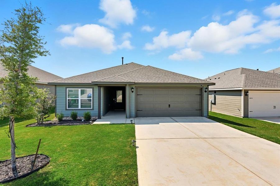 Ranch-style home with a shingled roof, a front lawn, concrete driveway, and an attached garage