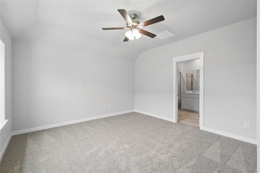 Unfurnished bedroom featuring carpet floors, lofted ceiling, ensuite bath, and a ceiling fan Unfurnished bedroom featuring carpet floors, lofted ceiling, ensuite bath, and a ceiling fan