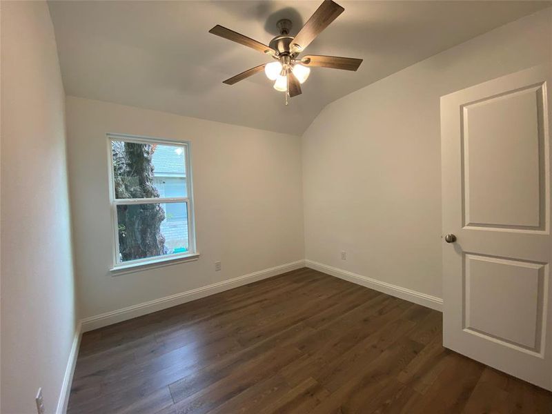 Bedroom with dark wood-style flooring, lofted ceiling, and ceiling fan Bedroom with dark wood-style flooring, lofted ceiling, and ceiling fan