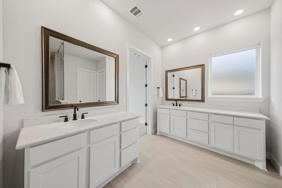 Another view of the primary bath highlighting the spacious dressing areas, framed mirrors and fixed window with obscure glass, providing diffused light and privacy.