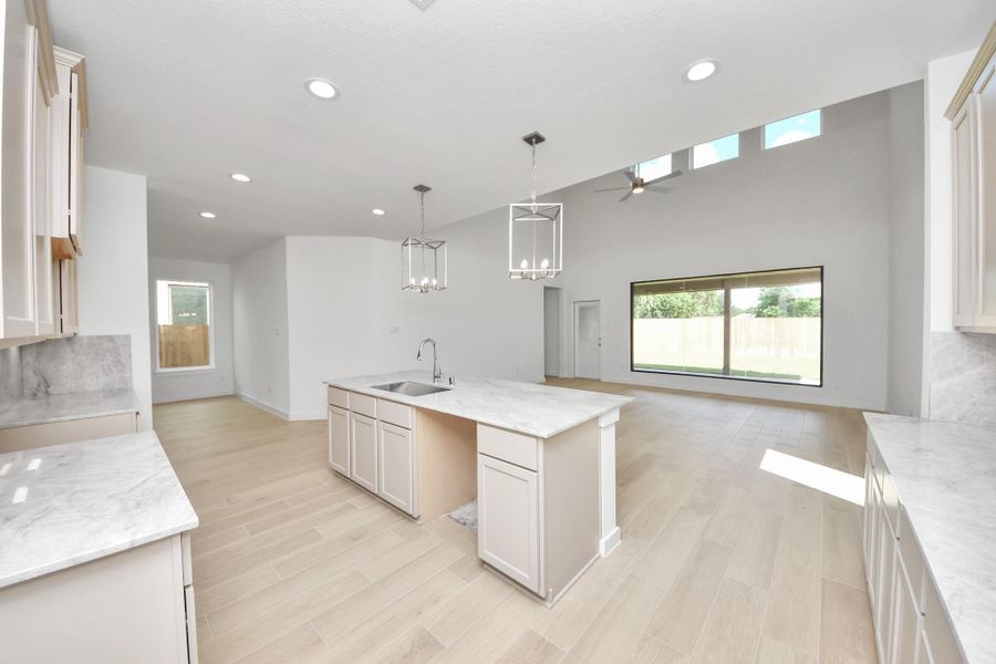This generously spacious kitchen is a dream realized! With a massive granite island, high ceilings, soft close cabinets, granite countertops, stainless steel appliances, a sleek tile backsplash, recessed lighting, and an extended counter area, it offers both style and practicality. All this opens up to the expansive family room, creating a perfect hub for gatherings. Sample photo of completed home with similar floor plan. Actual colors and selections may vary.
