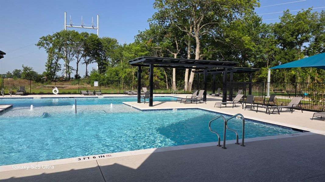 Outdoor swimming pool featuring a shallow water entry, multiple water features, and an integrated pergola structure Outdoor swimming pool featuring a shallow water entry, multiple water features, and an integrated pergola structure