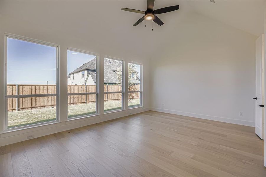 Unfurnished room featuring light wood finished floors, a ceiling fan, and high vaulted ceiling Unfurnished room featuring light wood finished floors, a ceiling fan, and high vaulted ceiling