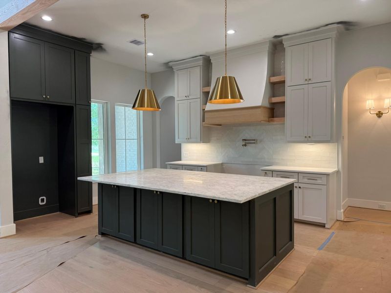 Kitchen featuring decorative backsplash, a kitchen island, arched walkways, recessed lighting, and light stone countertops